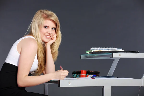 Blond meisje werken aan een tafel — Stockfoto