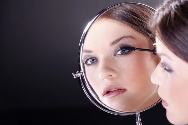 Młoda kobieta patrząc w lusterko kosmetyczne — Zdjęcie stockowe