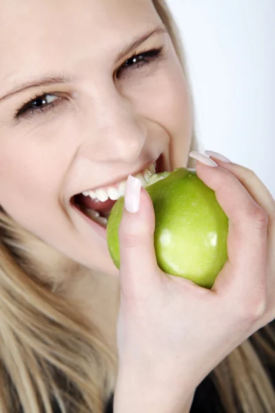 金髪の女性は、緑のリンゴを食べる — ストック写真