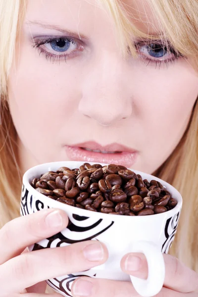 Affascinante giovane donna con un bel sorriso in possesso di una tazza di caffè bianco pieno di chicchi di caffè — Foto Stock