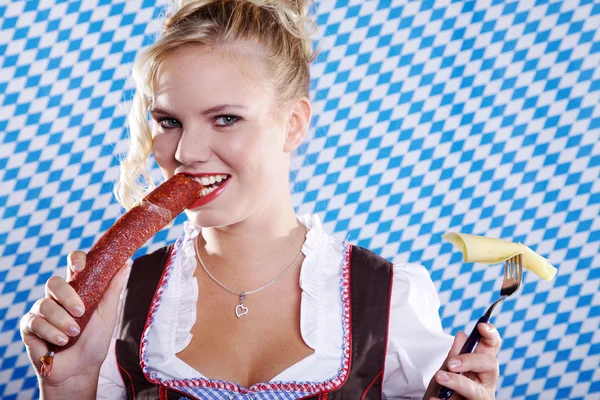 Girl in traditional clothes eating pancake with sausage — Stock Photo, Image