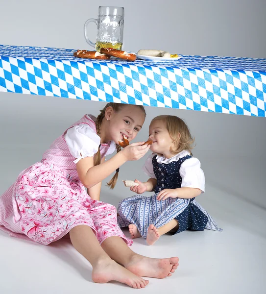 Two sisters under the table with food — Stock Photo, Image