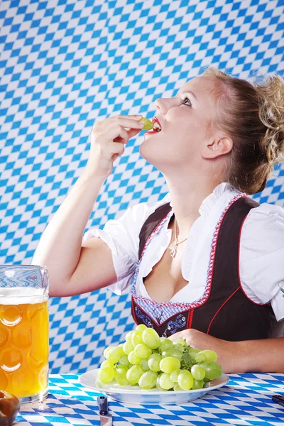 Girl in traditional clothes eating grapes — Stock Photo, Image