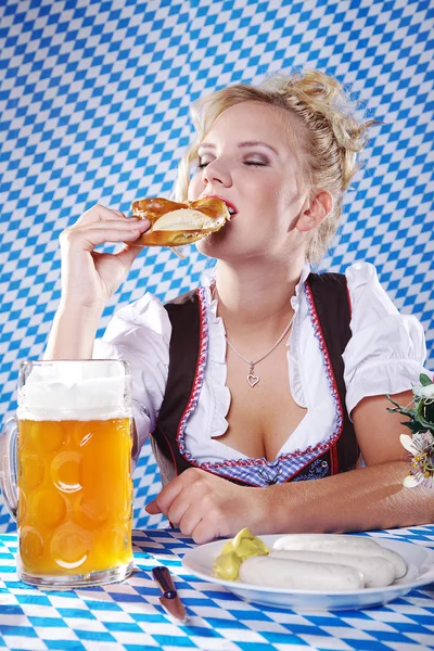 Happy woman in dirndl dloth holding Oktoberfest beer stein and pretzel in hands — Stock Photo, Image