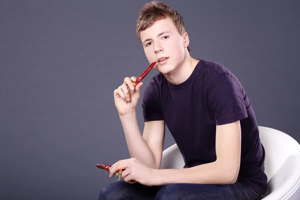 Boy eating red hot chili peppers — Stock Photo, Image