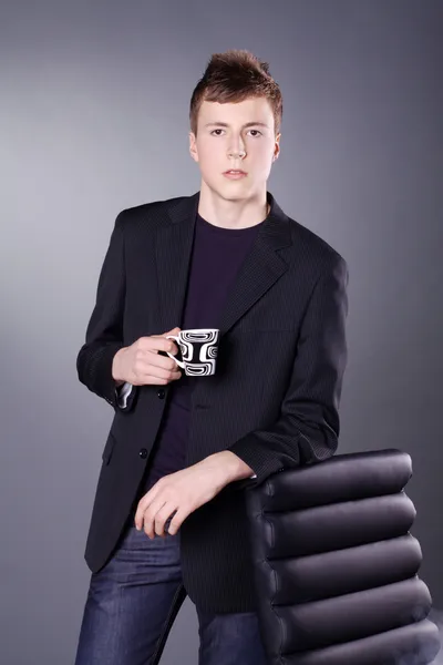 Ragazzo con una tazza di tè vicino alla sedia — Foto Stock
