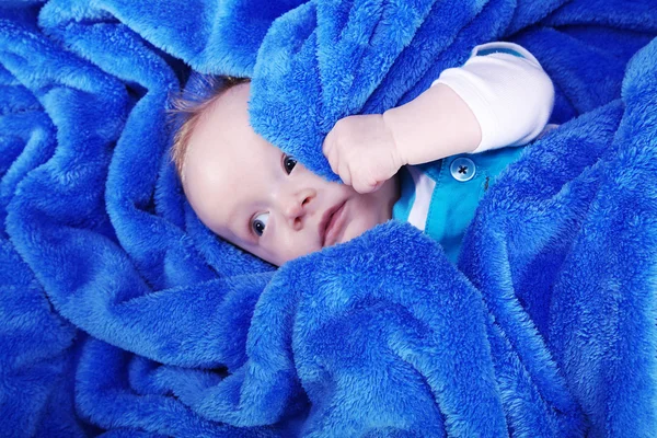 Mavi havlu sarılı küçük mutlu bir çocuk — Stok fotoğraf