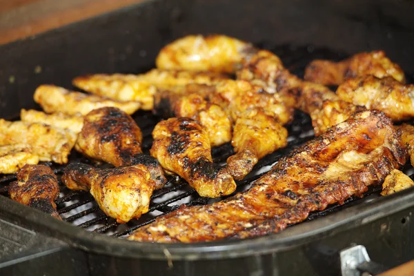 Chicken legs and ribs on the grill, across — Stock Photo, Image