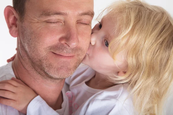 Pai segurando filha beijando-o sorrindo — Fotografia de Stock