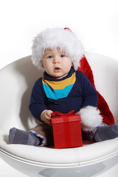 Little boy in a Christmas hat with a gift — Stock Photo, Image