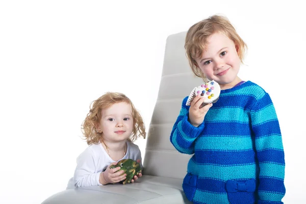 Duas meninas com um sapo de brinquedo e bolo — Fotografia de Stock