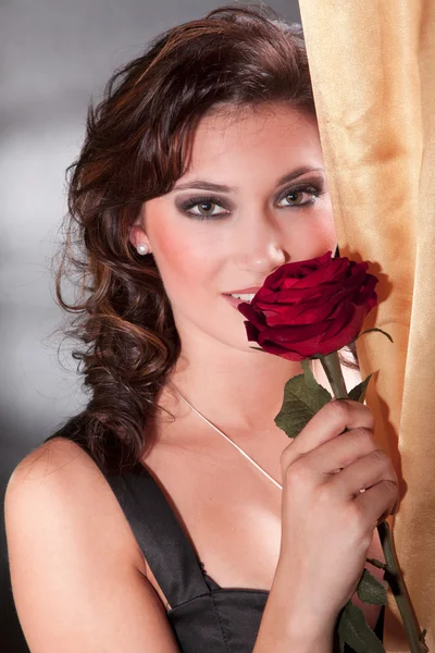 Ładna kobieta pachnąca czerwona róża — Zdjęcie stockowe