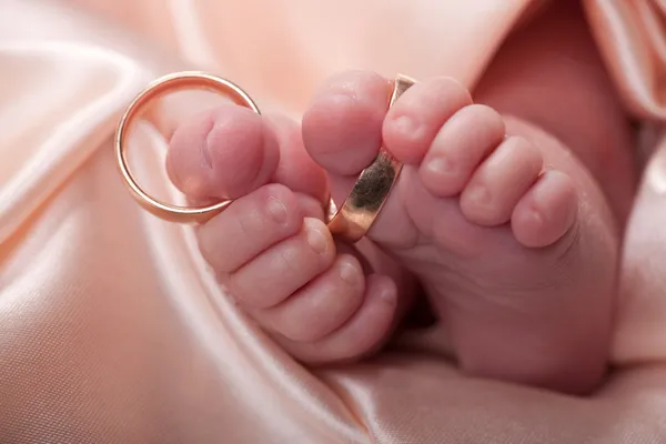 Baby feet with wedding rings — Stock Photo, Image