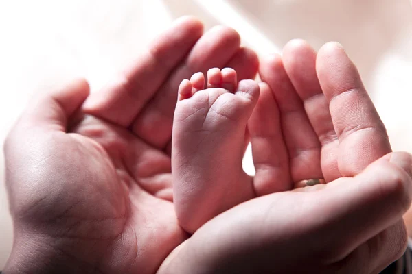 Moeder houden baby been samen in je hand — Stockfoto