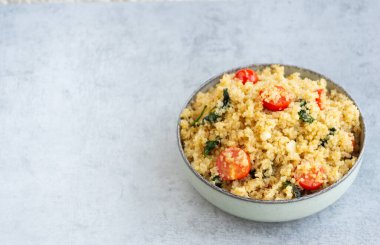 Vegetarian quinoa recipe with tomato, spinach and garlic. Horizontal, on a grey background with copy space. clipart