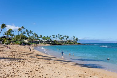Turist, Maui, Hawaii 'de beyaz kum ve kristal berrak suyla tropikal plajın tadını çıkarıyor.
