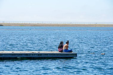 Arkadaşların mutluluğu. Yong kızları ahşap iskelede oturuyor ve dinleniyorlar..