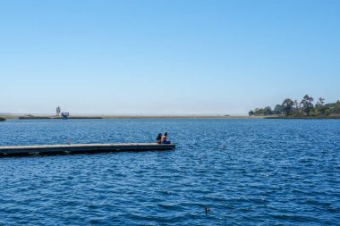 Arkadaşların mutluluğu. Yong kızları ahşap iskelede oturuyor ve dinleniyorlar..