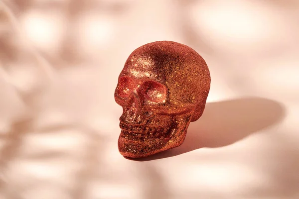 オレンジ色の頭蓋骨で覆われたスパンコールのベージュの背景に影 — ストック写真