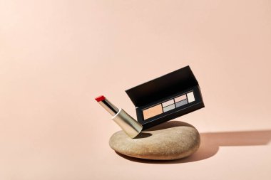 Kırmızı ruj ve göz farı paleti bir nehir çakıl taşı üzerinde kopya alanı ile. 