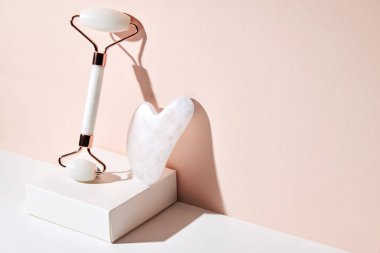 Beyaz kuvars yüz masajı Jade roller, Gua Sha, bej arka planda fotokopi alanı ile. SPA güzellik tedavi konsepti