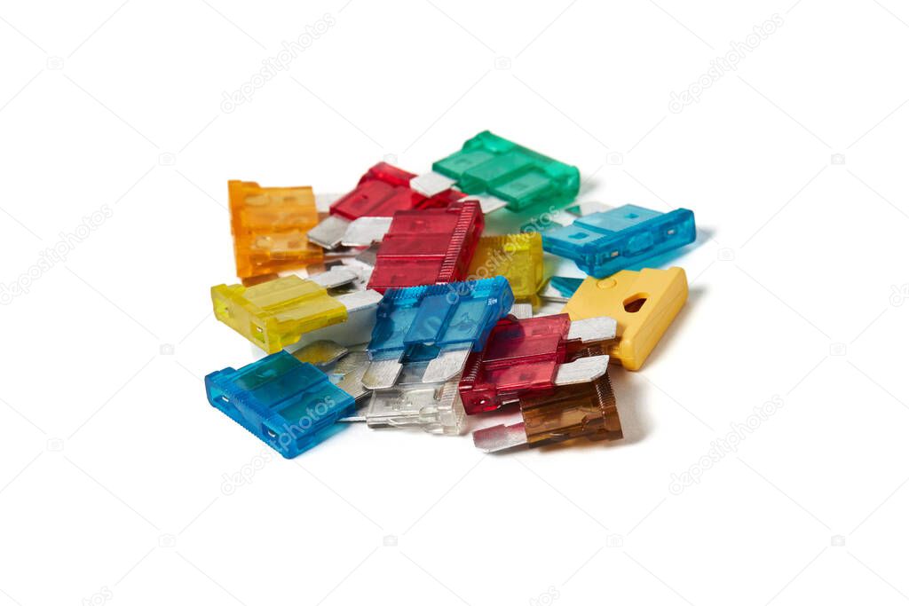 Pile of electrical automotive car fuses isolated on white background. Closeup of color coded blade type overcurrent protectors.