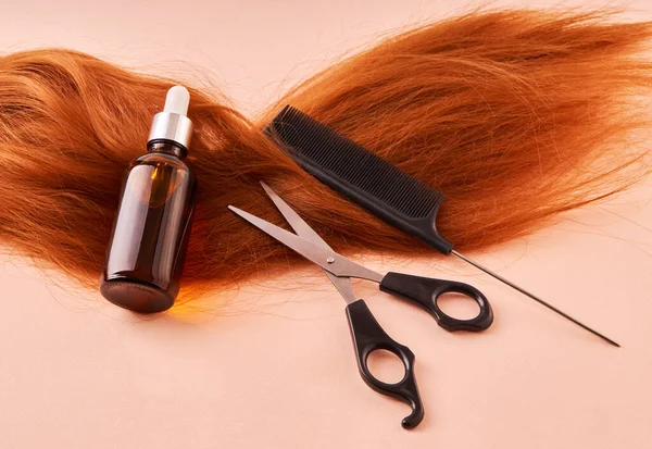 ガラス瓶 はさみ 櫛で化粧油とベージュの背景に赤い髪 ヘアサロン ヘアカット ヘアケアの概念 — ストック写真