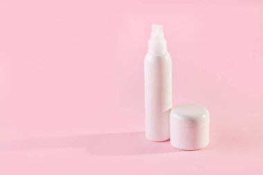 Fotokopi alanı olan pembe arka planda kozmetik ürünleri olan iki beyaz plastik kavanoz.