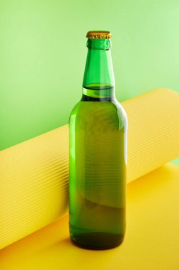 Yeşil cam şişe limonata ya da yeşil ve sarı arka planda bira.