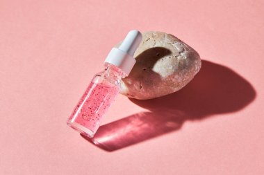 Pembe arka planda şeffaf bir cam şişede çivi ve tırnak serumu fırçala. Güzellik ve sağlık hizmetleri kavramı