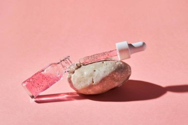 Pembe arka planda şeffaf bir cam şişede çivi ve tırnak serumu fırçala. Güzellik ve sağlık hizmetleri kavramı