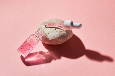 Pembe arka planda şeffaf bir cam şişede çivi ve tırnak serumu fırçala. Güzellik ve sağlık hizmetleri kavramı