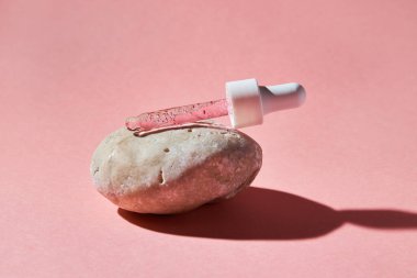 Pembe arka planda şeffaf bir cam şişede çivi ve tırnak serumu fırçala. Güzellik ve sağlık hizmetleri kavramı