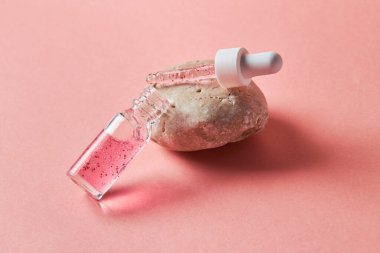 Pembe arka planda şeffaf bir cam şişede çivi ve tırnak serumu fırçala. Güzellik ve sağlık hizmetleri kavramı