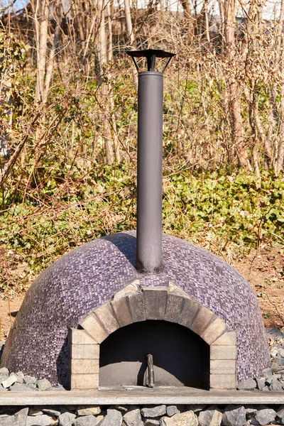 Outdoor stove for baking bread and pizza. Wood fired pizza oven decorated with small mosaic tiles