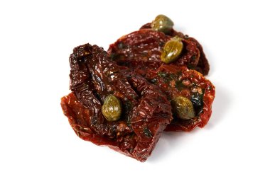 Beyaz zemin üzerinde kapari bulunan güneşte kurutulmuş domatesler.