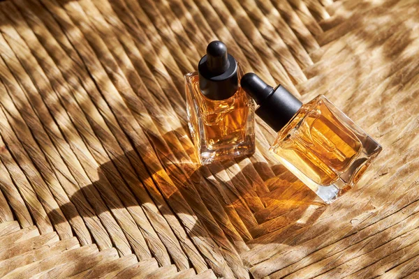 Cam şişelerde çivi ve tırnak bakımı için şeffaf yağ ve gölgeli doğal arka planda pipet makinesi. Güzellik ve bakım konsepti. 