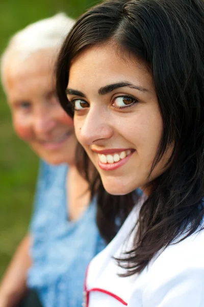 Sorridente donna anziana all'aperto con medico / infermiere — Foto Stock