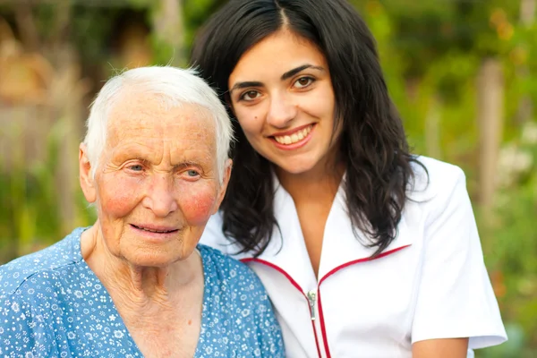 Yaşlı kadın açık havada doktor ile gülümseyen/hekim / hemşire — Stok fotoğraf