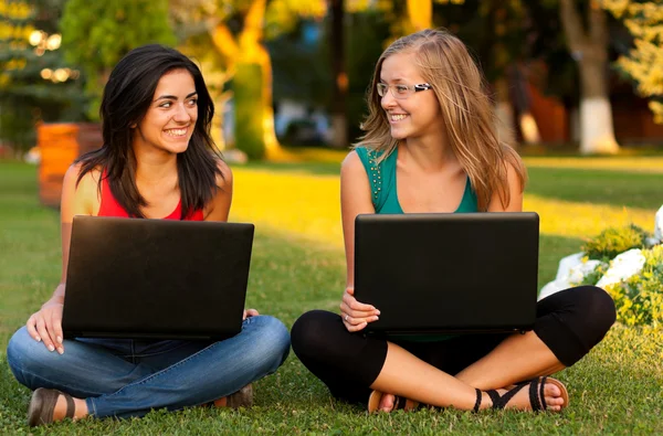 Vriendinnen met laptops zitten — Stockfoto