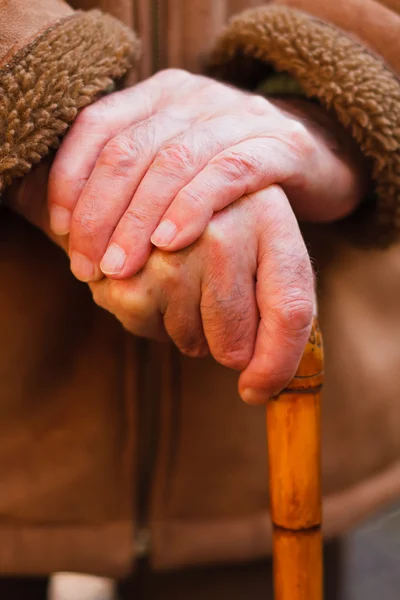 Äldre händerna vilande på käpp — Stockfoto