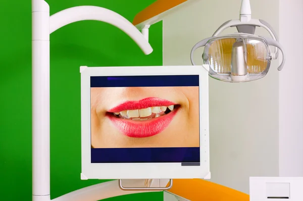 Una exhibición con una imagen de una hermosa sonrisa dentada, parte de la silla del dentista . —  Fotos de Stock
