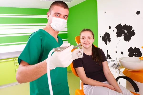 Un dentista joven trabajando, tratando a una paciente joven . —  Fotos de Stock