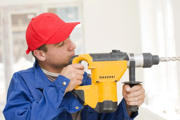 Um jovem segurando em sua mão uma grande broca, equipado com uma parte especial para concreto feito de um aço muito resistente . — Fotografia de Stock