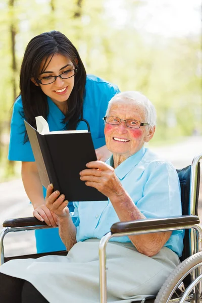 Ältere Dame im Rollstuhl liest — Stockfoto