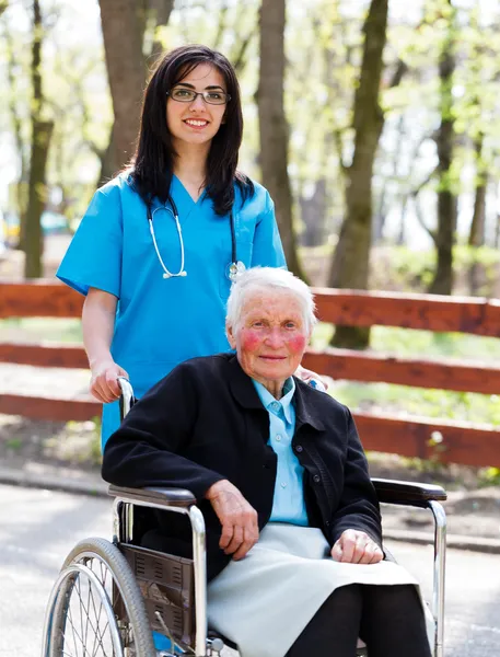 Caminhando com paciente sênior em cadeira de rodas — Fotografia de Stock