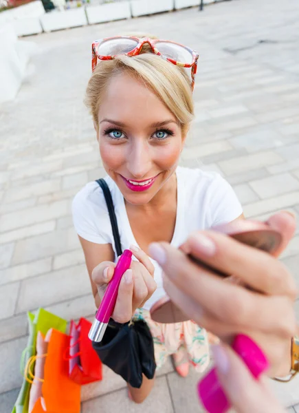 Preciosa mujer aplicando brillo labial después de ir de compras — Foto de Stock