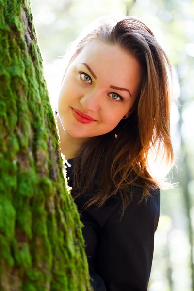 Mooie vrouw achter een boom — Stockfoto