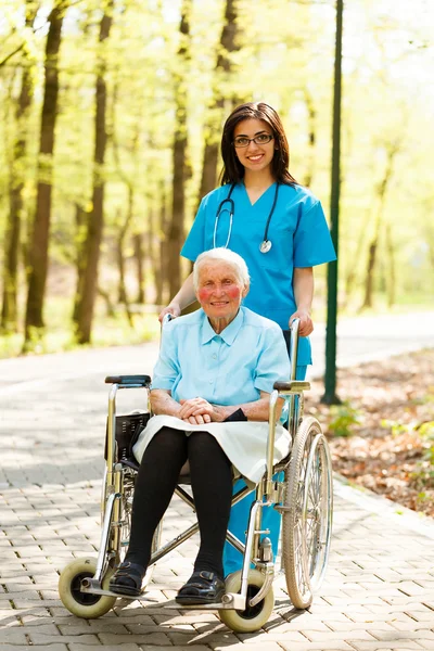 Infirmière avec dame âgée en fauteuil roulant — Photo