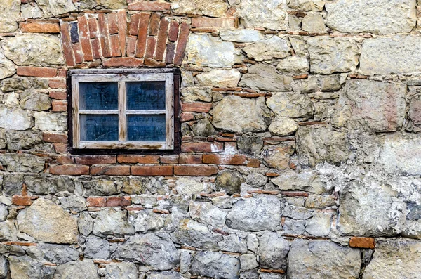 Litet fönster på en stenmur — Stockfoto